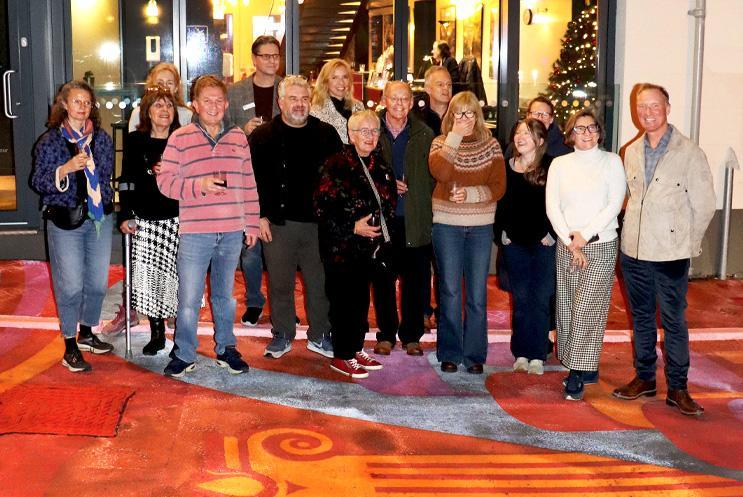 A group of people stood outside the theatre in the evening.