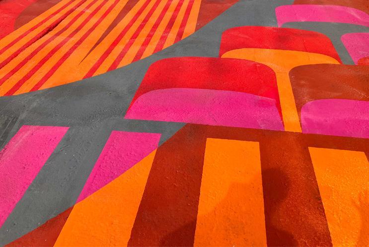 The artwork on the road in shades of red, orange, pink and grey.