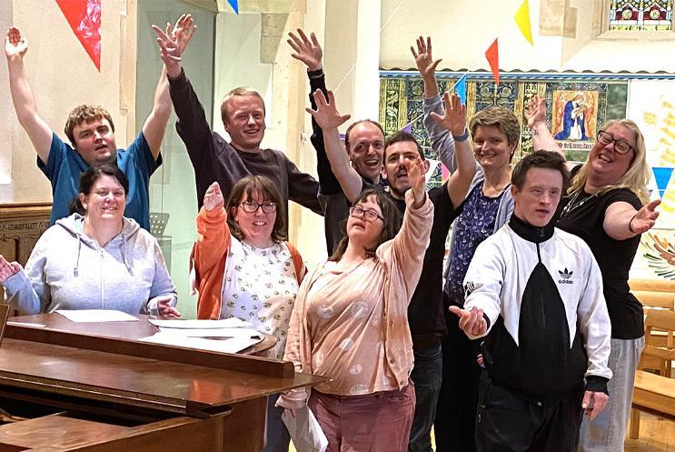 A group stood beside a piano with their hands in the air