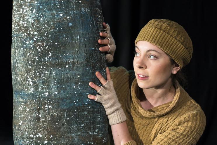 I young woman peering around a tree