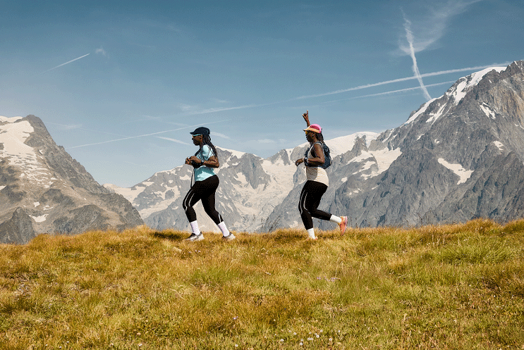 Two trail runners, running in the mountains