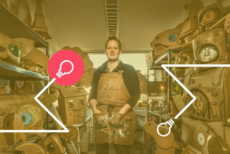 Sam Wilde surrounded by props and creations made from cardboard