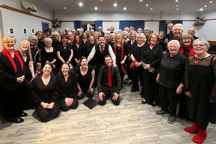 A big group all dressed in black and smiling at the camera.