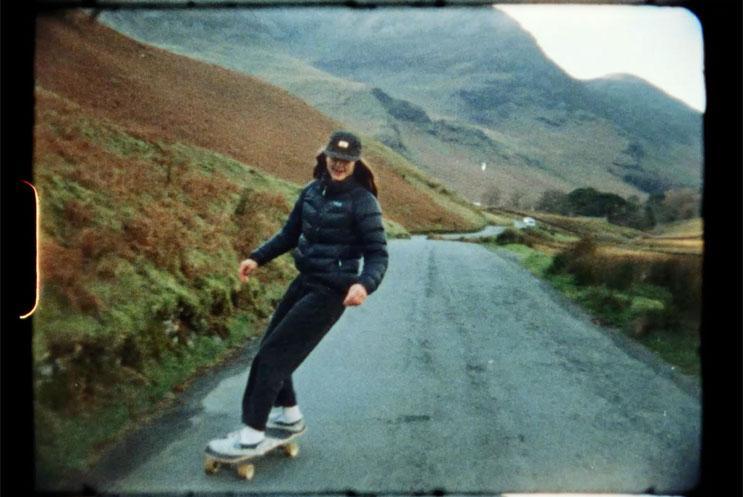 A woman on a skateboard on a mountainous road.
