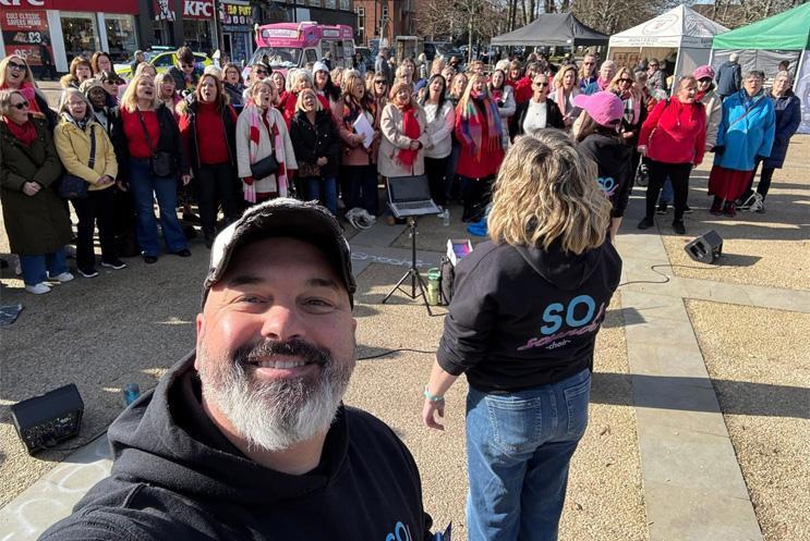 A man taking a selfie with a choir in the background